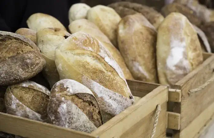 Loaves of homemade bread in wooden crates at an outdoor farmer's market.